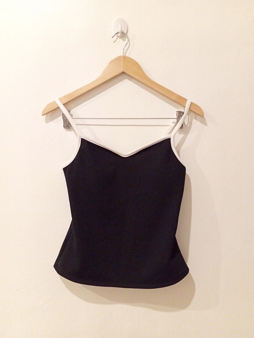 Black Tank Top with White Trim (Category: Sleeveless) located in Manila. Submitted by cococlo_ (Listing ID 1426444134, Image 1). Description: Black tank top features a white trim along the neckline and straps. It has a simple, classic design. The tank top is hanging on a wooden hanger. The straps are thin and the neckline is a V-shape..