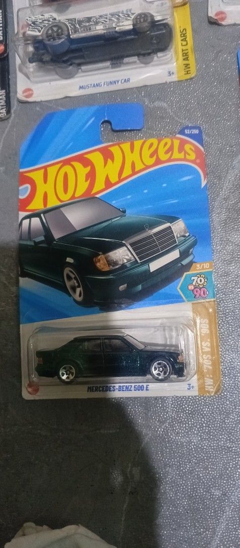 Hot Wheels Mercedes-Benz 500 E (Category: Vehicle & Diecast Models) located in Navotas City. Submitted by 777renmarktrinidad (Listing ID 1426405281, Image 1). Description: Hot Wheels Mercedes-Benz 500 E diecast car. It is a dark green color. The car is still in its original packaging. The packaging includes the Hot Wheels logo and the car's name. The car is part of the 2022 series..