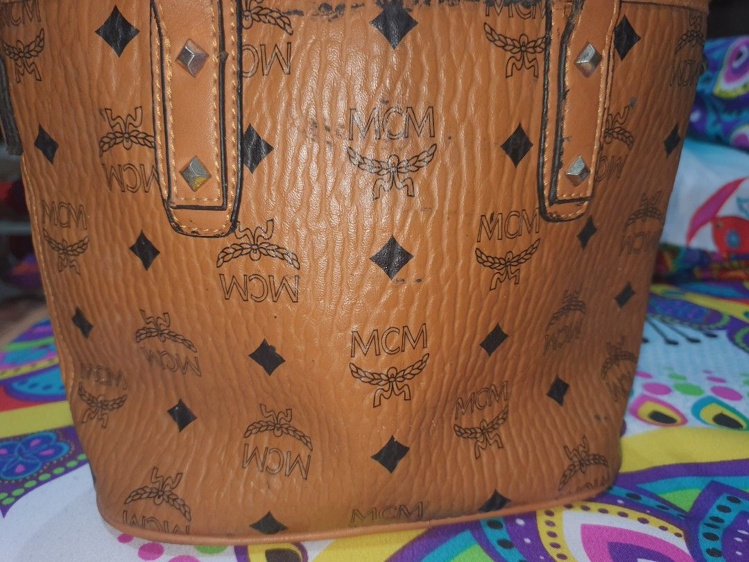 MCM Brown Tote Bag (Category: Luxury Bags & Wallets) located in Manila. Submitted by jemiclat3076761 (Listing ID 1426551901, Image 1). Description: MCM tote bag features a brown exterior with the brand's logo pattern. It has a top handle and a detachable shoulder strap. The bag includes a small metal plate with the MCM logo. The bag has some signs of wear..