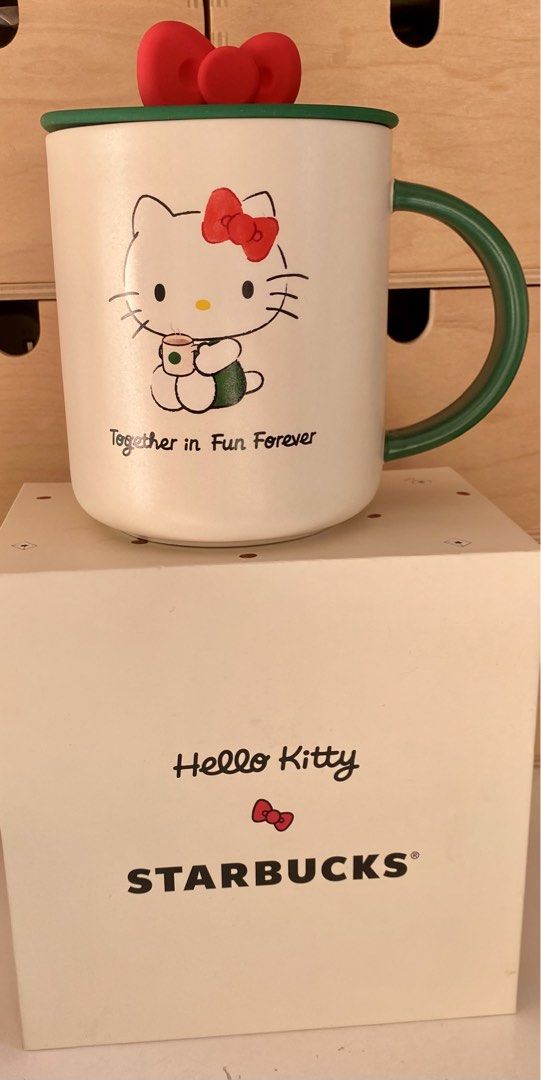 Starbucks Hello Kitty Ceramic Mug with Lid (Category: Coffee & Tea Tableware) located in Pasay City. Submitted by trendystash (Listing ID 1426487040, Image 1). Description: Brand new with box Starbucks mug features a Kitty design with a red bow on the lid. It has a green handle and a green lid. The mug is 16 fl. oz. / 473 mL and is microwave and dishwasher safe. The mug is a 2024 Sanrio licensed product..