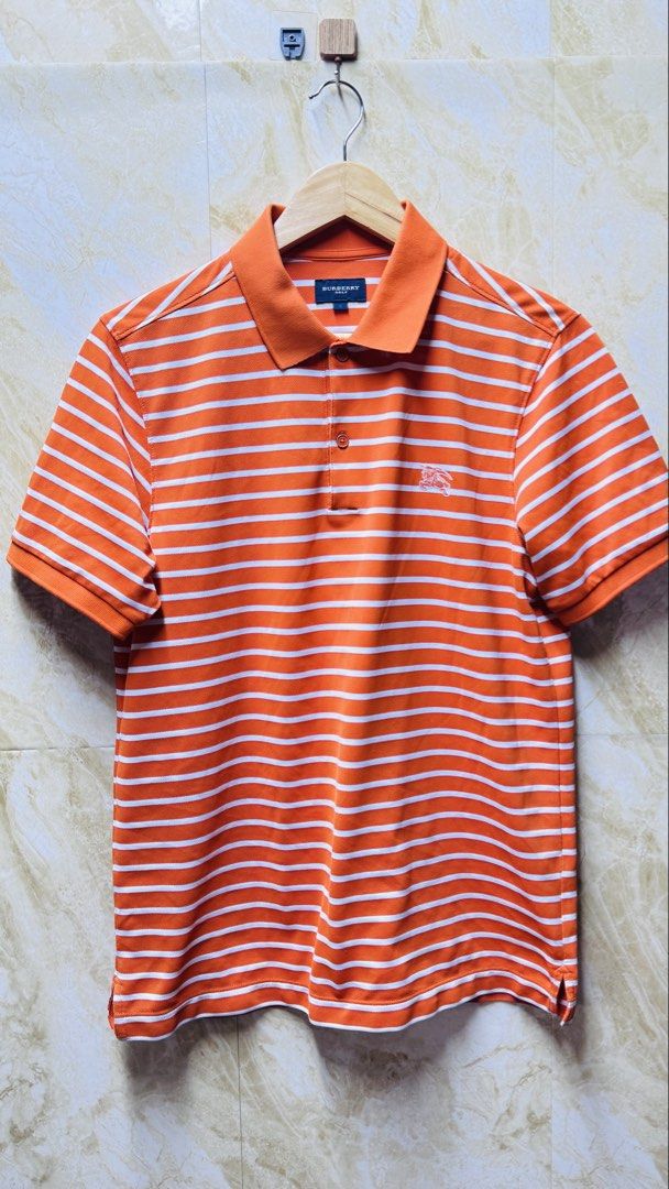 Authentic Burberry Golf Striped Polo Shirt (Category: Luxury Apparel) located in Batangas. Submitted by cjayf (Listing ID 1426640846, Image 1). Description: Orange and white striped polo shirt from Burberry Golf. Features the Burberry logo on the chest. The shirt has a collared neckline and short sleeves. Size 3. Made in Japan. Dimes 20x27.