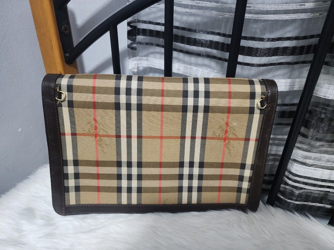 Burberry Clutch Bag (Category: Luxury Bags & Wallets) located in Paranaque City. Submitted by rizasauthenticitems (Listing ID 1426641781, Image 3). Description: Classic Burberry clutch bag featuring the iconic check pattern. It has a brown leather trim and a magnetic closure. The interior includes a small zippered pocket and a gold chain strap. The bag is marked "Made in England"..