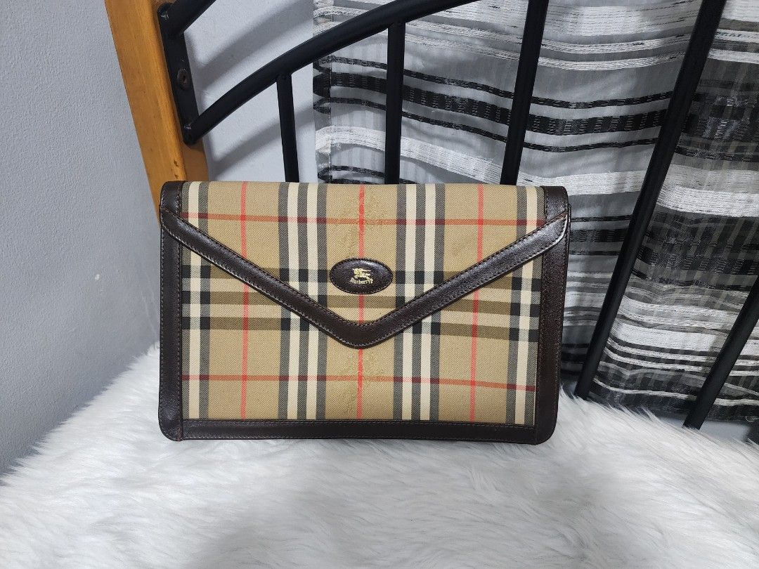 Burberry Clutch Bag (Category: Luxury Bags & Wallets) located in Paranaque City. Submitted by rizasauthenticitems (Listing ID 1426641781, Image 2). Description: Classic Burberry clutch bag featuring the iconic check pattern. It has a brown leather trim and a magnetic closure. The interior includes a small zippered pocket and a gold chain strap. The bag is marked "Made in England"..