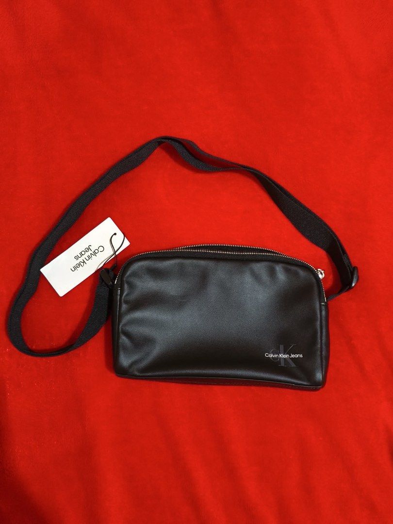 Calvin Klein Jeans Crossbody Bag (Category: Cross-body Bags) located in Muntinlupa City. Submitted by gepdeg (Listing ID 1426673034, Image 1). Description: Black crossbody bag from Calvin Klein Jeans. Features a main compartment with a zipper closure. Includes an adjustable strap and a Calvin Klein Jeans logo on the front. The interior has a Calvin Klein Jeans label. Comes with original tags..