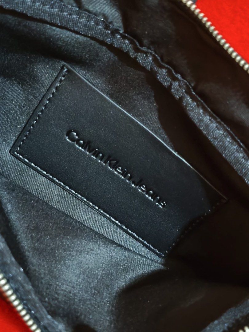 Calvin Klein Jeans Crossbody Bag (Category: Cross-body Bags) located in Muntinlupa City. Submitted by gepdeg (Listing ID 1426673034, Image 3). Description: Black crossbody bag from Calvin Klein Jeans. Features a main compartment with a zipper closure. Includes an adjustable strap and a Calvin Klein Jeans logo on the front. The interior has a Calvin Klein Jeans label. Comes with original tags..