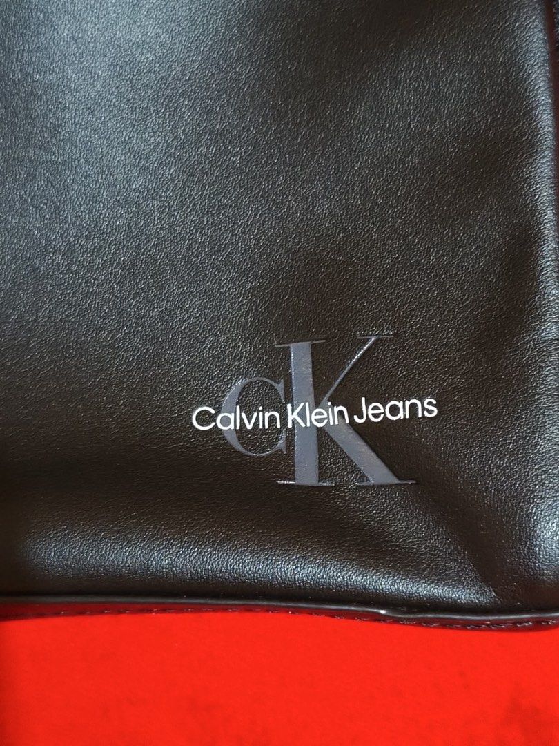 Calvin Klein Jeans Crossbody Bag (Category: Cross-body Bags) located in Muntinlupa City. Submitted by gepdeg (Listing ID 1426673034, Image 2). Description: Black crossbody bag from Calvin Klein Jeans. Features a main compartment with a zipper closure. Includes an adjustable strap and a Calvin Klein Jeans logo on the front. The interior has a Calvin Klein Jeans label. Comes with original tags..