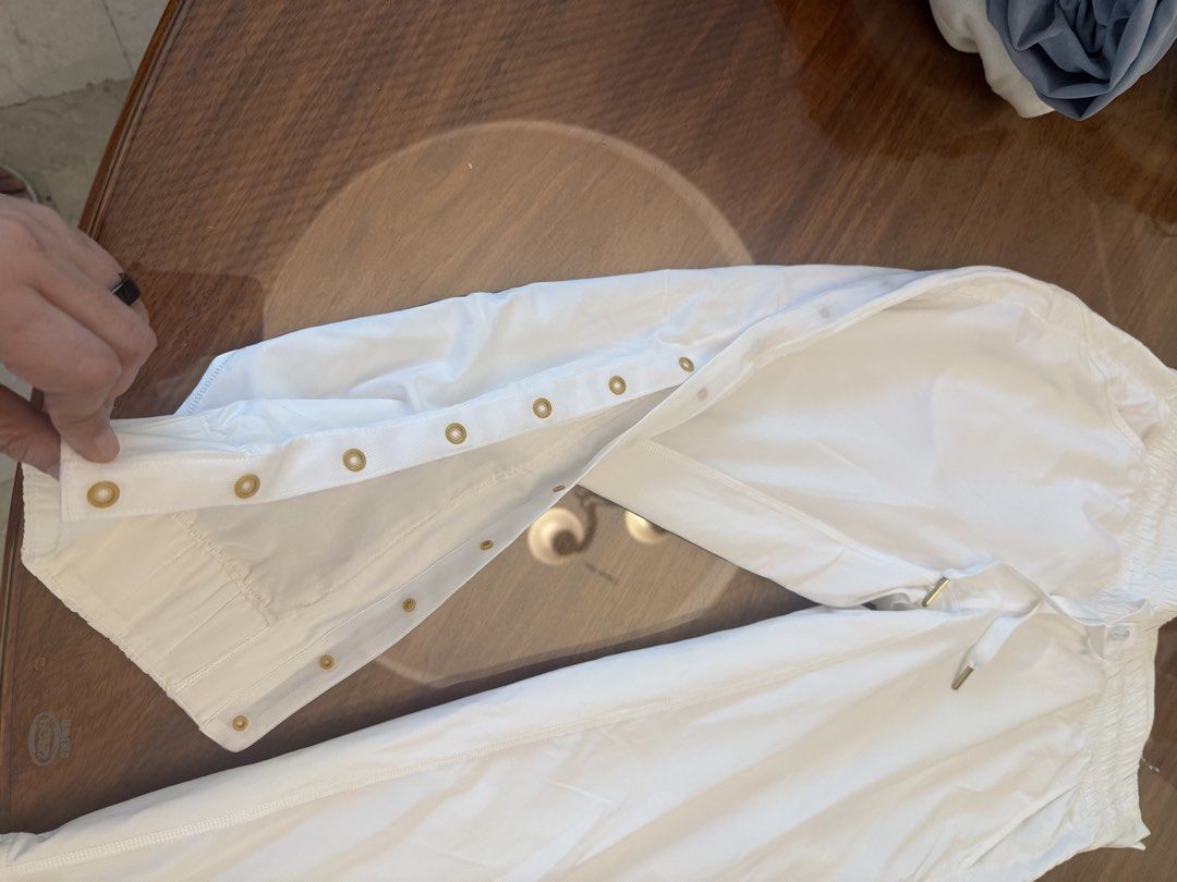 Lululemon Athletica White Pants Size 4 (Category: Other Bottoms) located in Muntinlupa City. Submitted by secondchancechic (Listing ID 1426653664, Image 2). Description: White Lululemon Athletica pants. Features a drawstring waist and snap button details along the sides. The size tag indicates a size 4. Made with a blend of polyester, nylon, and spandex. Designed in the Philippines..