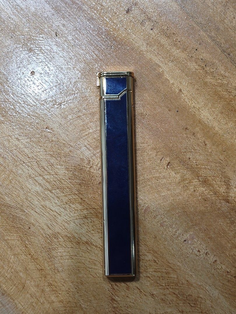 Martell Cognac Lighter (Category: Vintage Collectibles) located in Candon. Submitted by ylocos_thrifts (Listing ID 1426748571, Image 3). Description: Vintage lighter featuring the Martell Cognac branding. It has a rectangular shape with a gold-colored frame and a blue center. The lighter is marked with the "Martell Cognac" logo in a cursive font. The images show the lighter in both open and closed positions..