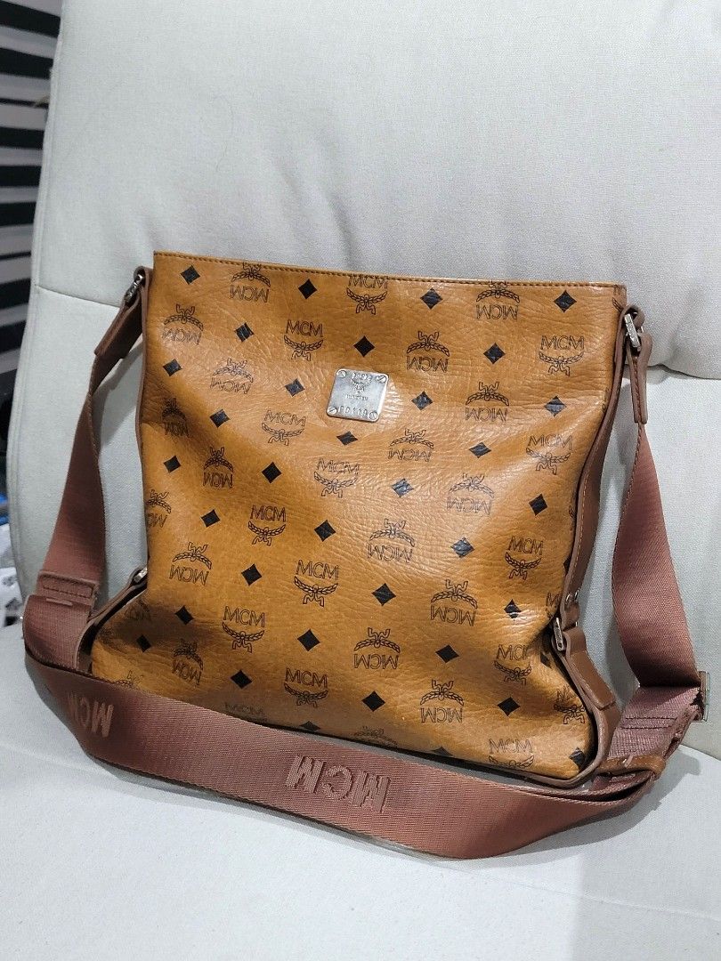 Guaranteed Authentic MCM Messenger Sling Bag (Category: Luxury Bags & Wallets) located in Antipolo. Submitted by dlolin (Listing ID 1426719357, Image 1). Description: Still super nice. Laptop and Tablet won't fit MCM messenger bag in a brown monogram pattern. Features a shoulder strap with MCM branding. Includes a main compartment and an interior pocket. The bag has a metal plate with the MCM logo and a serial number. Made in Korea..