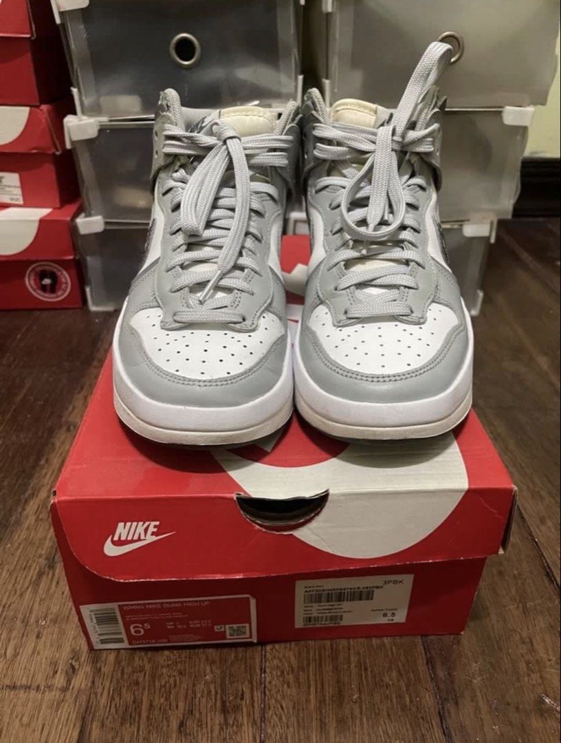 Original Nike Womens Dunk High Up Smoke Grey (Category: Sneakers) located in Manila. Submitted by miiitch (Listing ID 1426705357, Image 3). Description: Nike WMNS Dunk High Up sneakers in white and grey. Size 6.5 US. Features a white base with grey overlays and a silver swoosh. Includes the original box. The soles show minimal wear. .
