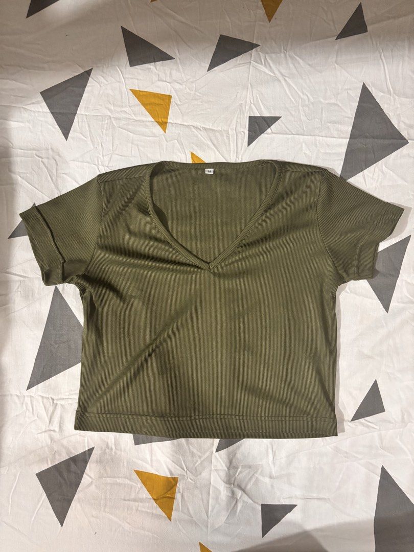 Olive Green V-Neck Ribbed Top (Category: Sleeveless) located in Manila. Submitted by mscyaa.declutter (Listing ID 1426747230, Image 1). Description: Olive green ribbed top with a V-neck. Features short sleeves with folded cuffs. The fabric has vertical ribbing. Cropped length. Medium on tag.