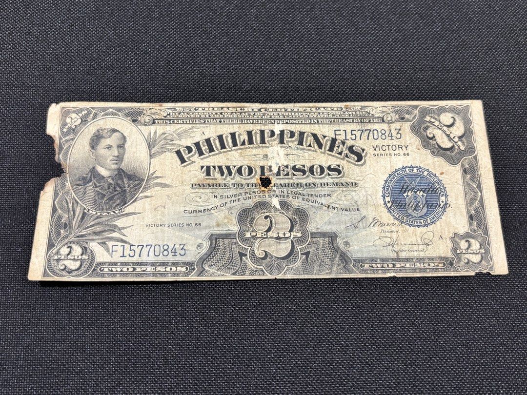 Philippines Two Pesos Victory Series Banknote (Category: Currency) located in Manila. Submitted by _minimalist__ (Listing ID 1426697955, Image 1). Description: Philippines Two Pesos Victory Series banknote. It features a portrait of a man on the front and the word "VICTORY" on the back. The banknote has the serial number F15770843. There are some signs of wear and tear, including a hole and some damage along the edges..