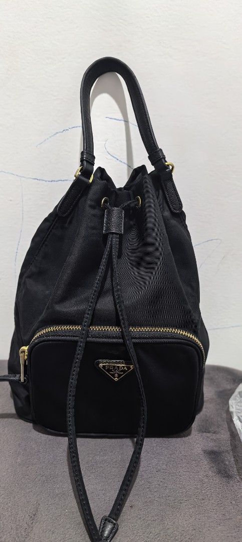 Prada Drawstring Bucket Bag (Category: Luxury Bags & Wallets) located in Cagayan de Oro. Submitted by tommygurl1218 (Listing ID 1426789940, Image 1). Description: - Prada bucket bag - Black nylon material - Leather top handle - Gold-tone hardware - Front zip pocket with Prada logo - Drawstring closure With sling slot (to make it as sling/ crossbody bag).