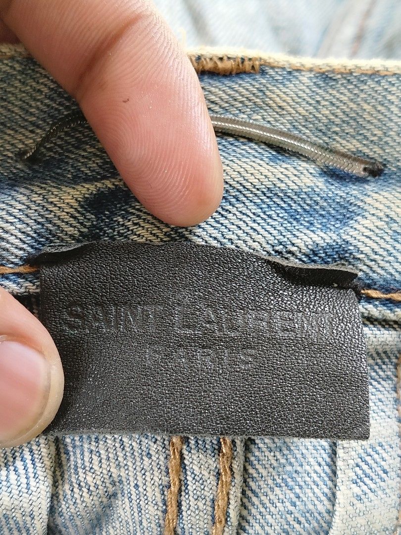 Saint Laurent Paris Distressed Jeans (Category: Luxury Apparel) located in Ilagan. Submitted by goodsanddeals-a73c28 (Listing ID 1426790872, Image 3). Description: - Distress design Authentic Saint Laurent Paris jeans. Features a light blue wash with heavy distressing throughout the front and back. Includes the Saint Laurent Paris logo on the button and leather patch. Size 32. Made in Japan. Includes the original Saint Laurent logo pin..