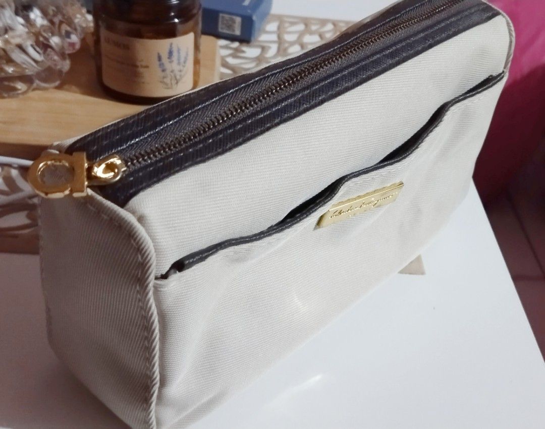 Salvatore Ferragamo Cosmetic Bag (Category: Luxury Bags & Wallets) located in Dasmarinas. Submitted by hachiifinds (Listing ID 1426705556, Image 2). Description: Authentic Salvatore Ferragamo cosmetic bag. Features a beige exterior with a brown zipper and trim. Includes a gold-tone zipper pull and a small front pocket. The interior lining has a repeating pattern..