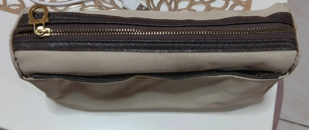 Salvatore Ferragamo Cosmetic Bag (Category: Luxury Bags & Wallets) located in Dasmarinas. Submitted by hachiifinds (Listing ID 1426705556, Image 3). Description: Authentic Salvatore Ferragamo cosmetic bag. Features a beige exterior with a brown zipper and trim. Includes a gold-tone zipper pull and a small front pocket. The interior lining has a repeating pattern..