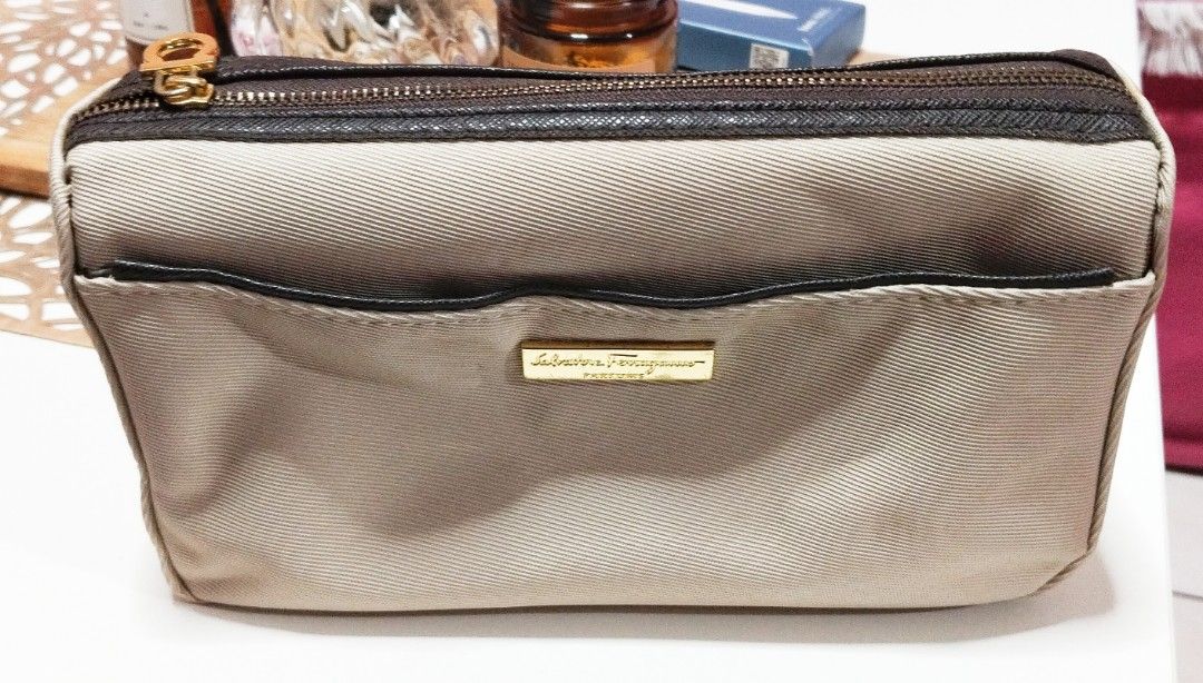 Salvatore Ferragamo Cosmetic Bag (Category: Luxury Bags & Wallets) located in Dasmarinas. Submitted by hachiifinds (Listing ID 1426705556, Image 1). Description: Authentic Salvatore Ferragamo cosmetic bag. Features a beige exterior with a brown zipper and trim. Includes a gold-tone zipper pull and a small front pocket. The interior lining has a repeating pattern..