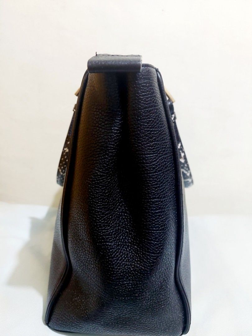Samantha Thavasa Black Handbag (Category: Luxury Bags & Wallets) located in Taguig. Submitted by chic_n_geek_instyle (Listing ID 1426605579, Image 3). Description: Black handbag from Samantha Thavasa. Features gold-toned hardware and a textured leather exterior. Includes a patterned handle and a detachable strap. The bag has a zipper closure and a spacious interior. The brand name is displayed prominently on the front of the bag. change strap.