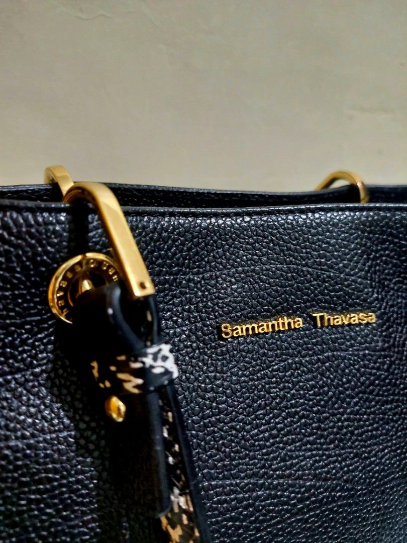 Samantha Thavasa Black Handbag (Category: Luxury Bags & Wallets) located in Taguig. Submitted by chic_n_geek_instyle (Listing ID 1426605579, Image 2). Description: Black handbag from Samantha Thavasa. Features gold-toned hardware and a textured leather exterior. Includes a patterned handle and a detachable strap. The bag has a zipper closure and a spacious interior. The brand name is displayed prominently on the front of the bag. change strap.