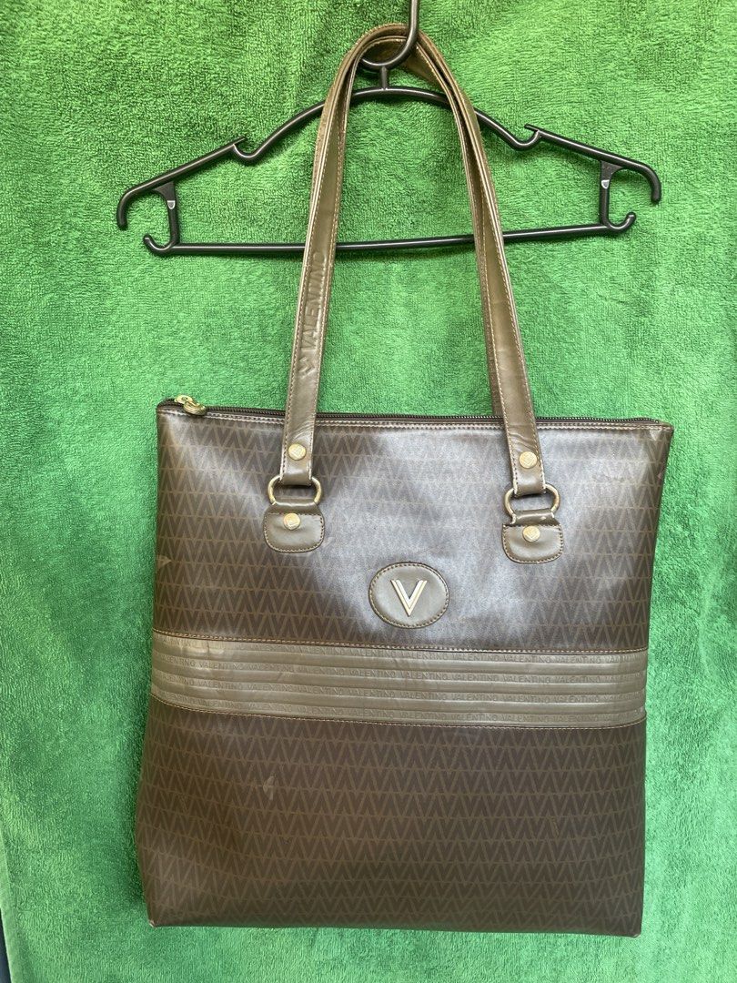 Valentino Tote Bag (Category: Luxury Bags & Wallets) located in Cavite. Submitted by msandysgoodies (Listing ID 1426647488, Image 1). Description: Flaw: starting to bubble ( not totally) Signs of usage on the handle. Fits 14-inch laptop Valentino tote bag with a brown monogram pattern. Features a top zipper closure and double top handles. The bag has a brown and olive green color scheme. The interior has a single compartment with a zipper pocket.