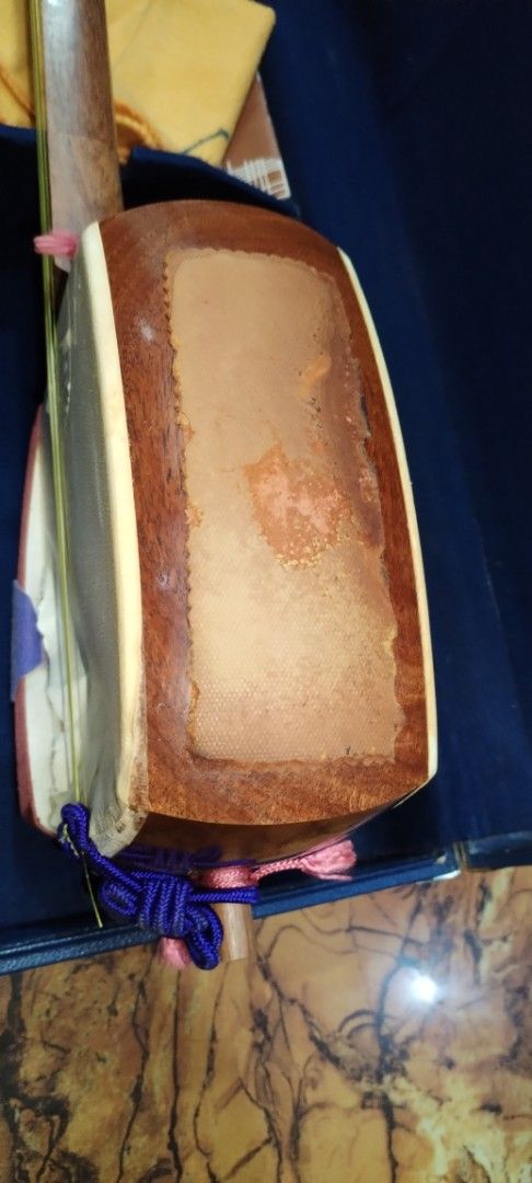 Vintage Shamisen with Case (Category: Musical Instruments) located in Caloocan City. Submitted by rowely_jpn (Listing ID 1426603290, Image 2). Description: Traditional Japanese Shamisen, complete with its original case. The instrument features a wooden body and neck, with visible wear on the soundboard. Included are accessories such as a tuning peg, bridge, and other components. The case is lined with blue fabric and has compartments for storage.