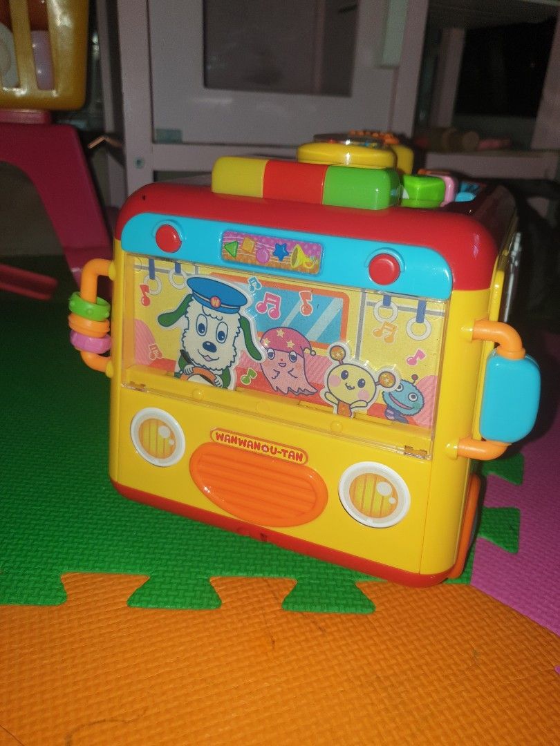 wanwan&u-tan musical busy bus (Category: Infant Playtime) located in Quezon City. Submitted by krmariam13 (Listing ID 1426599061, Image 2). Description: Colorful musical activity cube toy features various interactive elements, including buttons, gears, and shape sorters. It has a bus design with cartoon characters and lights. It also has a handle for easy carrying..