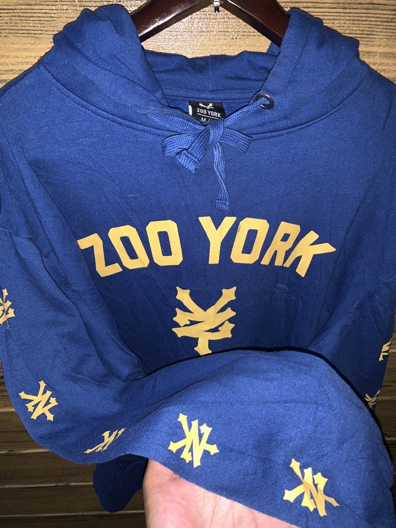 Zoo York Hoodie (Category: Hoodies) located in Valenzuela. Submitted by Caloooy (Listing ID 1426742585, Image 3). Description: Blue Zoo York hoodie with yellow logo and sleeve details. Features a drawstring hood and a kangaroo pocket. The size is M/M. The hoodie has the Zoo York logo on the front and the sleeves. 600+sf.
