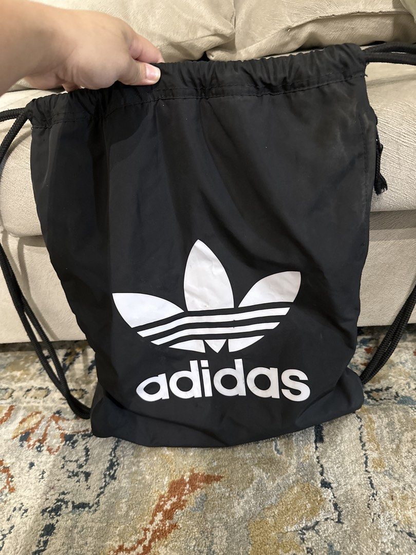 Adidas Drawstring Bag (Category: Backpacks) located in Taguig. Submitted by anglsaints (Listing ID 1426849922, Image 1). Description: Black Adidas drawstring bag. Features the iconic Adidas trefoil logo in white. Includes black drawstring straps for easy carrying. Perfect for carrying gym clothes, shoes, or other essentials. A simple and stylish bag for everyday use..