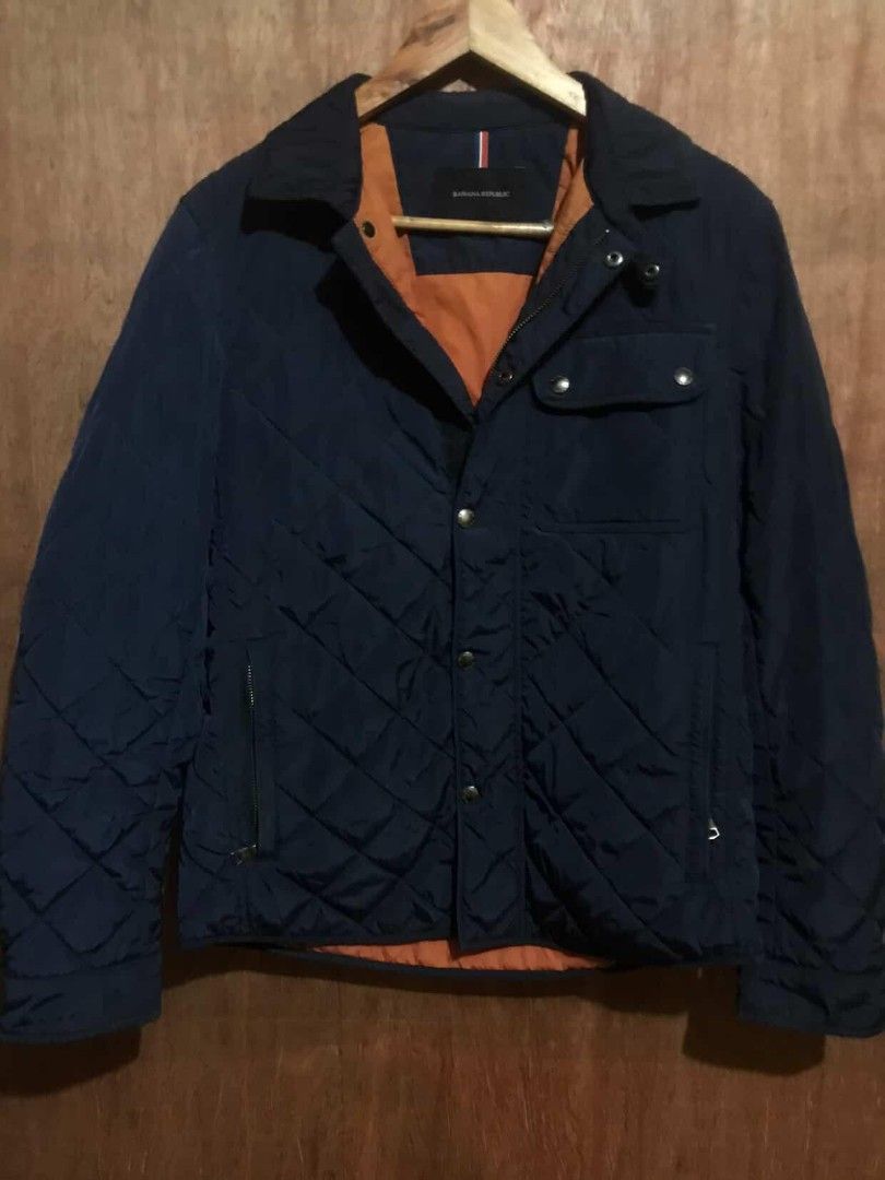 Banana Republic Quilted Jacket (Category: Coats, Jackets and Outerwear) located in Manila. Submitted by ronmark (Listing ID 1426815592, Image 1). Description: Navy blue quilted jacket from Banana Republic. Features an orange lining and button closure. Includes two front pockets and a zippered pocket. The jacket has the Banana Republic logo on the buttons. Made of 100% polyester..