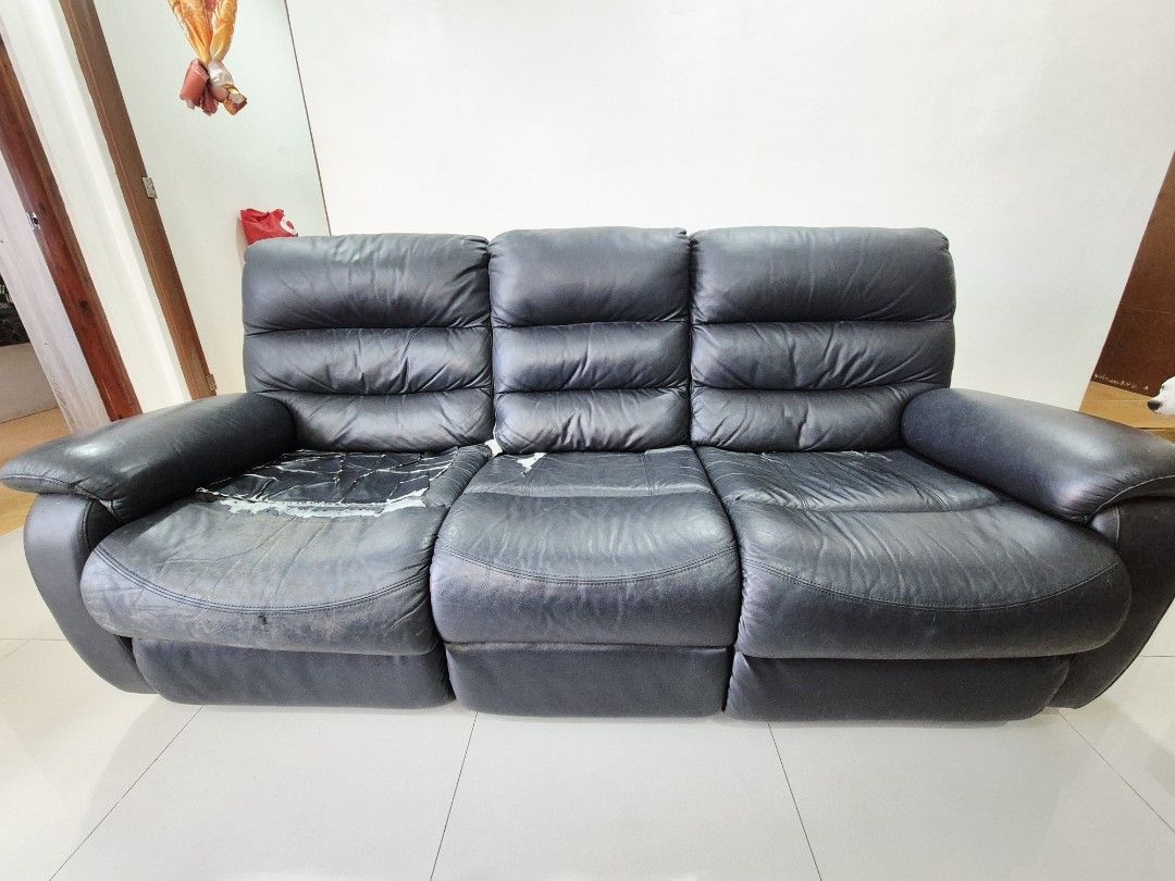 Black Leather Reclining Sofa (Category: Sofas) located in Quezon City. Submitted by khristinellanes (Listing ID 1426935934, Image 1). Description: Black leather reclining sofa. Features three seats with reclining sections. Visible wear and tear on the seating surfaces, including tears and peeling of the leather. The sofa has a solid base and armrests. Issue: For upholstery as seen on the photo. Binilhan lang namin ng beige na cover to hide yung n