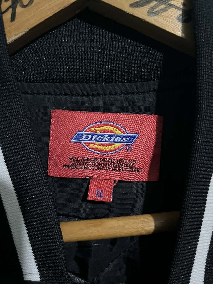 Dickies Black Varsity Jacket XL (Category: Coats, Jackets and Outerwear) located in Cabanatuan. Submitted by chinithou (Listing ID 1426843612, Image 3). Description: Black Dickies varsity jacket. Features the Dickies logo on the front and back. Includes a button-up closure and striped detailing on the collar, cuffs, and hem. The jacket has an XL size tag. The interior has a quilted lining for added warmth and comfort..