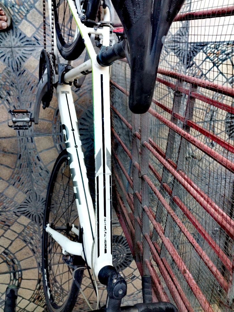 Giant Road Bike (Category: Bicycles) located in Mandaluyong City. Submitted by josephbatulan (Listing ID 1426884052, Image 2). Description: White Giant road bike with black handlebars and seat. Features Shimano Altus rear derailleur. Includes black tires and a black and silver crankset. The bike has a white frame with green and black accents. The bike has drop handlebars..