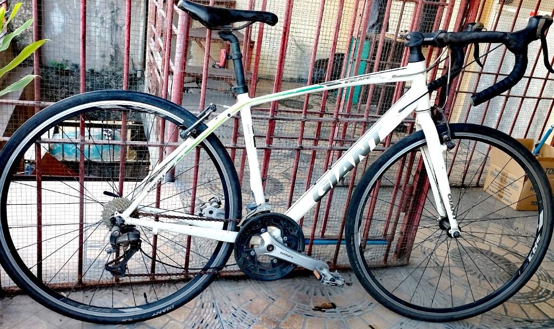 Giant Road Bike (Category: Bicycles) located in Mandaluyong City. Submitted by josephbatulan (Listing ID 1426884052, Image 1). Description: White Giant road bike with black handlebars and seat. Features Shimano Altus rear derailleur. Includes black tires and a black and silver crankset. The bike has a white frame with green and black accents. The bike has drop handlebars..