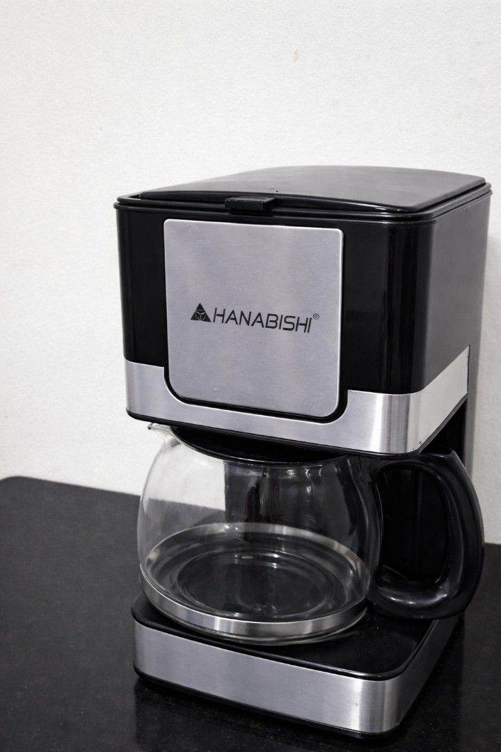 Hanabishi Coffee Maker (Category: Coffee Machines & Makers) located in Caloocan City. Submitted by mommymoon71 (Listing ID 1426852017, Image 1). Description: Hanabishi coffee maker features a black and silver design with a glass carafe. It has a visible water level indicator and a handle for easy pouring. The brand name is prominently displayed on the front..