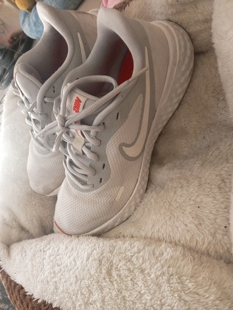 Nike Revolution 5 White Running Shoes (Category: Sneakers) located in Valenzuela. Submitted by beahocson (Listing ID 1426846109, Image 2). Description: Original Nike Revolution 5 running shoes in white. Features a white upper with a grey swoosh and accents. The soles are brown. The size is UK 7, EUR 40, and US 7. The style code is BQ3204-019. The shoes have some wear on the soles and some minor marks on the upper. Unisex for men and women, slight