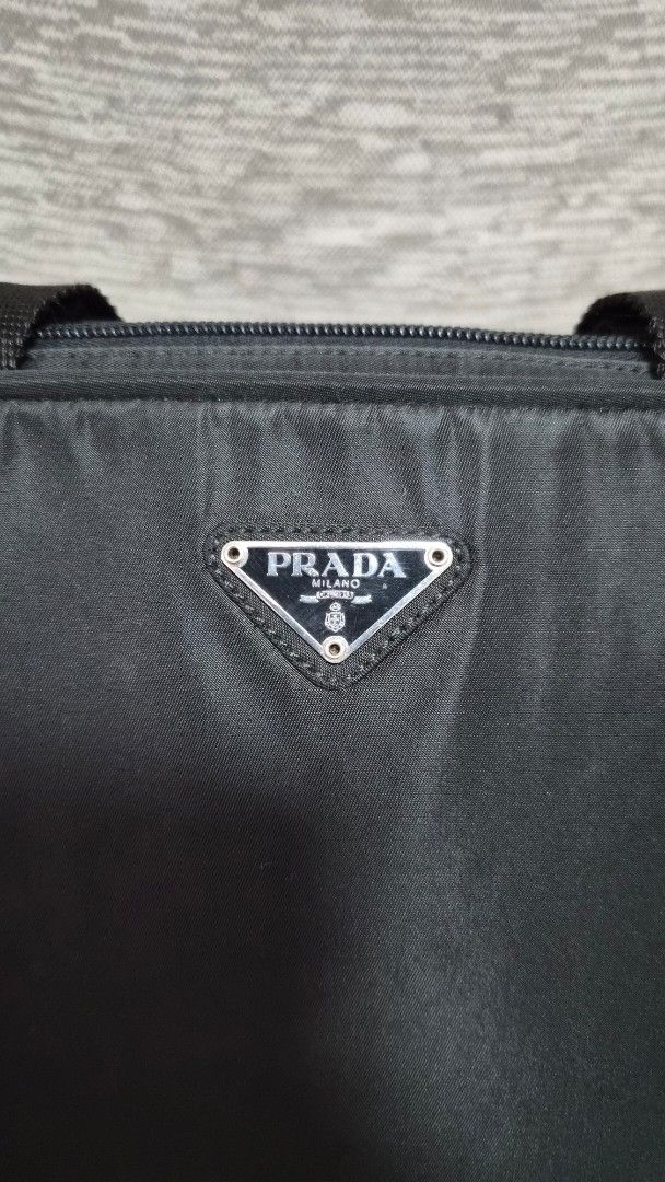 Preloved Prada Tessuto Nylon top-handle bag (Category: Luxury Bags & Wallets) located in Quezon City. Submitted by marya_s (Listing ID 1426824661, Image 3). Description: if namamahalan pa sa 9k wag na po mag Prada Authentic Prada handbag in black. Features a top handle design with a zip closure. Includes a lock and keys. The interior has a Prada logo. The bag has a classic shape with a nylon exterior. Includes a dust bag. The bag has metal feet o