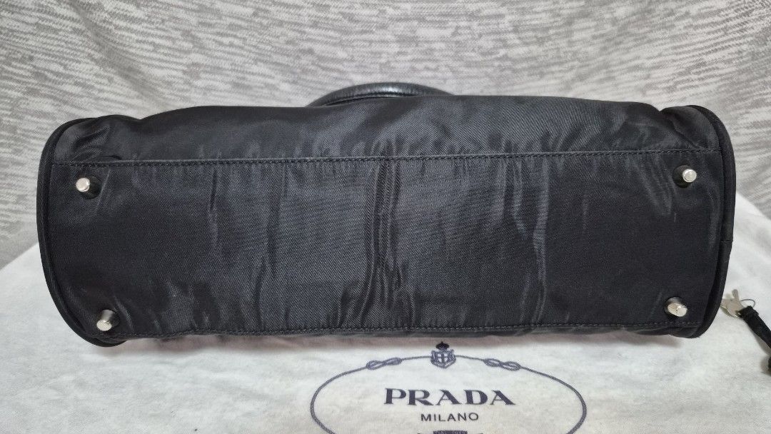 Preloved Prada Tessuto Nylon top-handle bag (Category: Luxury Bags & Wallets) located in Quezon City. Submitted by marya_s (Listing ID 1426824661, Image 2). Description: if namamahalan pa sa 9k wag na po mag Prada Authentic Prada handbag in black. Features a top handle design with a zip closure. Includes a lock and keys. The interior has a Prada logo. The bag has a classic shape with a nylon exterior. Includes a dust bag. The bag has metal feet o