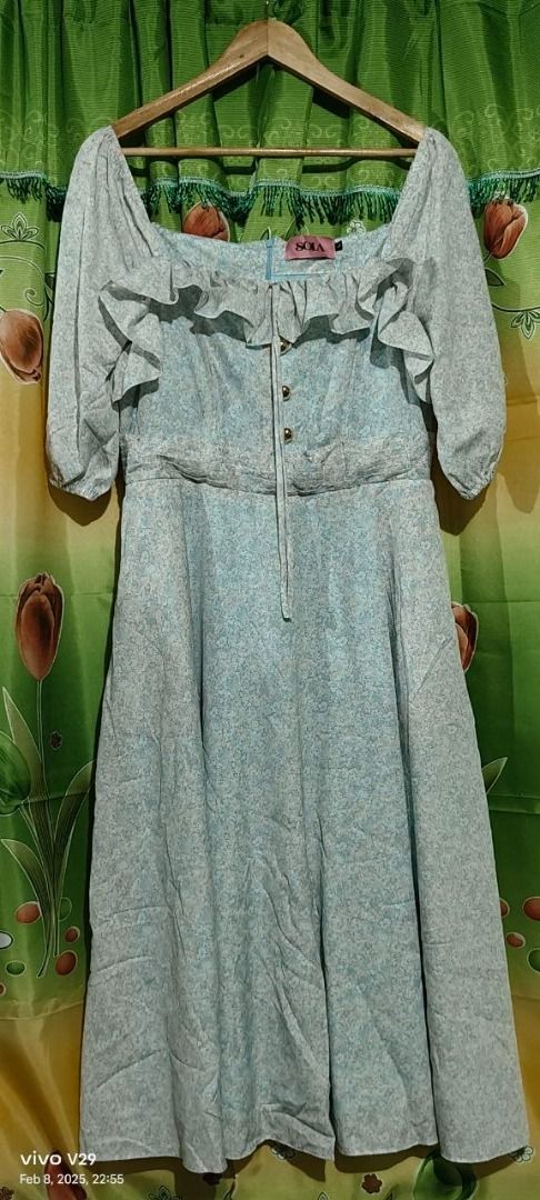 Sola Floral Dress (Category: Dresses) located in Quezon City. Submitted by ak_0406 (Listing ID 1426874882, Image 1). Description: Dress features a square neckline with ruffle details and three-quarter sleeves. It has a button-down front and a tie detail at the bust. The dress is a light blue color with a floral pattern and a midi length. The brand tag is visible..
