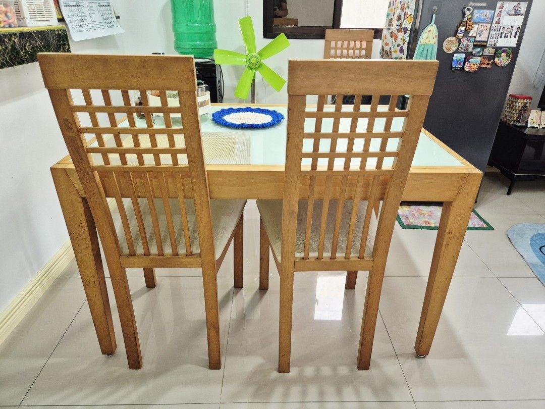 Solid Wood Expandable Dining Table with 4 Chairs (Category: Tables & Sets) located in Quezon City. Submitted by khristinellanes (Listing ID 1426937097, Image 2). Description: Expandable solid wood dining set with a tempered glass top and 4 matching chairs. The chairs have a lattice back design and cushioned seats. The table has a light wood finish. Issue: Need to repaint yung foot ng table and chairs..