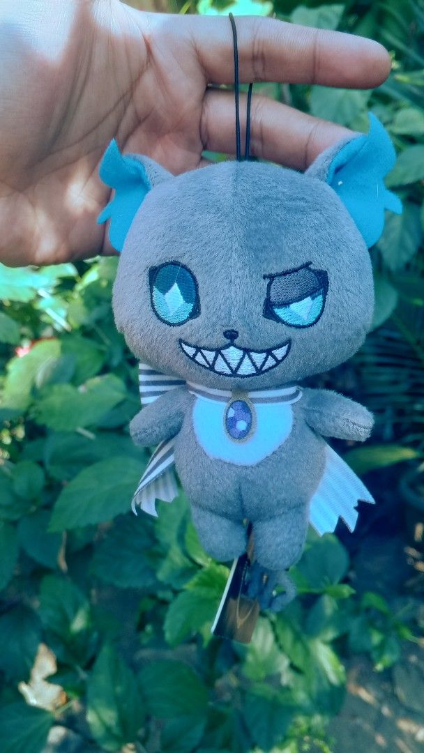 Twisted Wonderland Grim Charm Plushie (Category: Plushies & Soft Toys) located in Mamburao. Submitted by rogerhabbitz (Listing ID 1426874164, Image 1). Description: Adorable plushie featuring a character from Twisted Wonderland. It has a gray body with blue accents on the ears and eyes. The plushie has a bow and a tag attached. It is a cute collectible item..