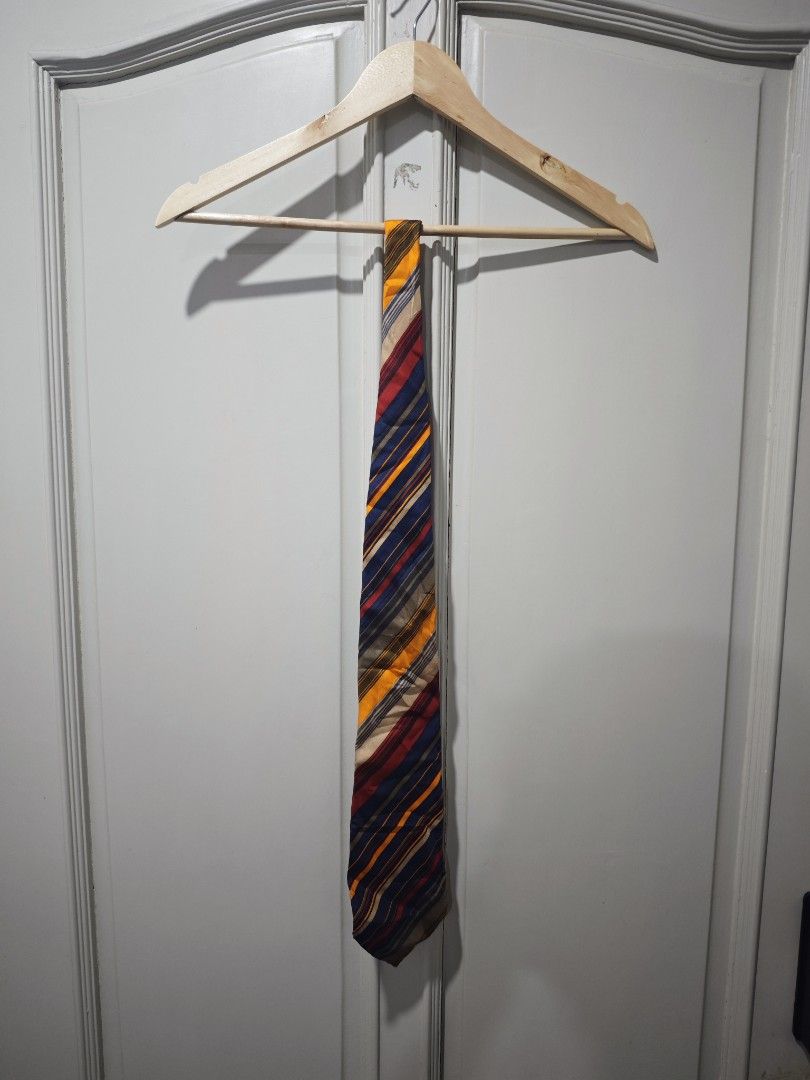 Yves Saint Laurent Striped Tie (Category: Ties) located in Iloilo. Submitted by declutterpm2 (Listing ID 1426858004, Image 1). Description: Stylish Yves Saint Laurent tie featuring a vibrant striped design. The tie showcases a mix of colors including blue, yellow, red, and beige. The brand's logo is visible on the back of the tie. A classic accessory to elevate any outfit..
