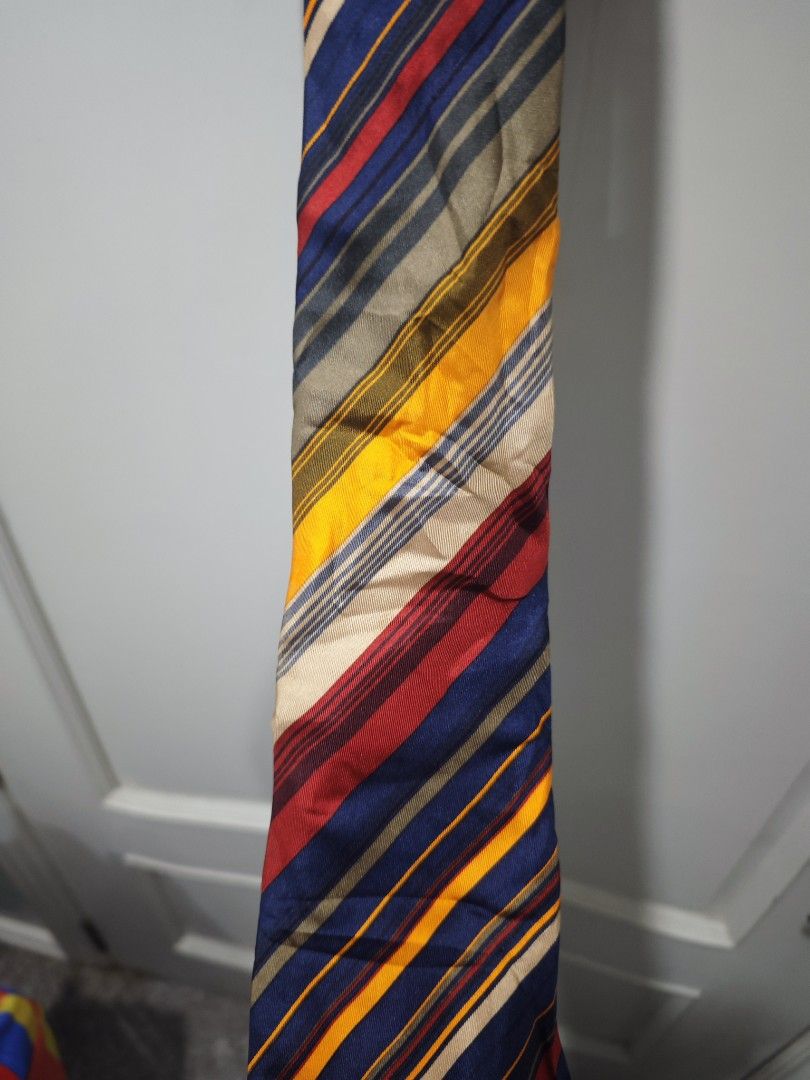 Yves Saint Laurent Striped Tie (Category: Ties) located in Iloilo. Submitted by declutterpm2 (Listing ID 1426858004, Image 2). Description: Stylish Yves Saint Laurent tie featuring a vibrant striped design. The tie showcases a mix of colors including blue, yellow, red, and beige. The brand's logo is visible on the back of the tie. A classic accessory to elevate any outfit..