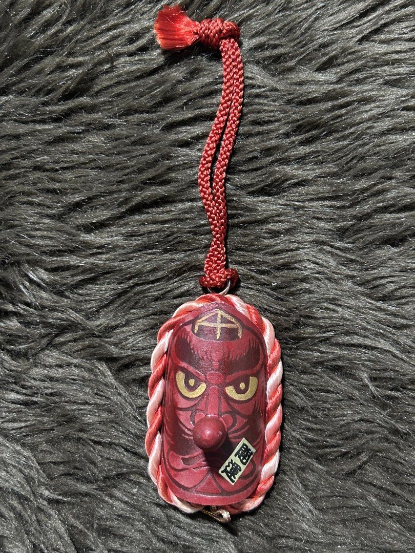 Japanese Tengu Charm (Category: Charms) located in Angeles City. Submitted by zyeplustradings (Listing ID 1427051294, Image 2). Description: Japanese Tengu charm. It features a red mask with gold accents and a long nose. The charm is decorated with a red and white braided rope. The back of the charm has Japanese characters. It has a red cord for hanging. 3 inches tall This item is a Japanese Wooden Tengu strap talisman, typically used as a lucky 