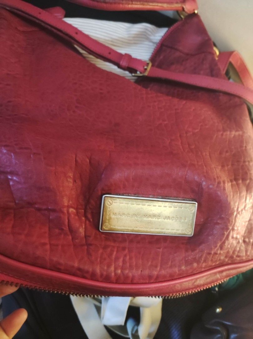 Marc by Marc Jacobs Leather Handbag (Category: Luxury Bags & Wallets) located in Zamboanga. Submitted by Clairey03 (Listing ID 1426988251, Image 2). Description: Red leather handbag by Marc by Marc Jacobs. It features a shoulder strap and a top handle. The bag has a zipper closure and a metal logo plate on the front. The leather has a textured appearance. There are some signs of wear on the handle and leather areas.