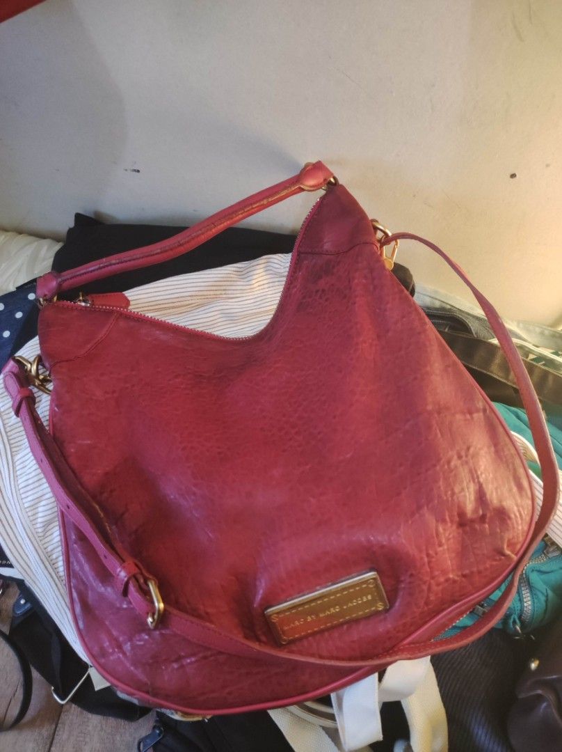 Marc by Marc Jacobs Leather Handbag (Category: Luxury Bags & Wallets) located in Zamboanga. Submitted by Clairey03 (Listing ID 1426988251, Image 1). Description: Red leather handbag by Marc by Marc Jacobs. It features a shoulder strap and a top handle. The bag has a zipper closure and a metal logo plate on the front. The leather has a textured appearance. There are some signs of wear on the handle and leather areas.