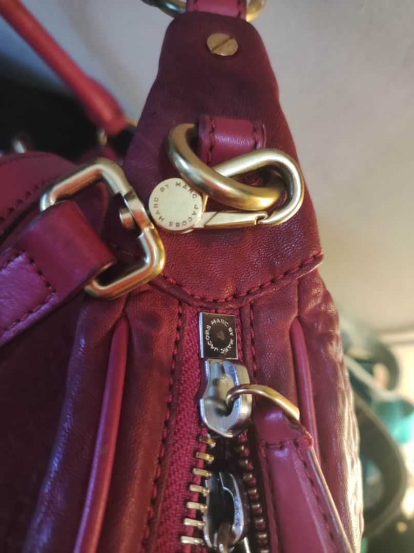 Marc by Marc Jacobs Leather Handbag (Category: Luxury Bags & Wallets) located in Zamboanga. Submitted by Clairey03 (Listing ID 1426988251, Image 3). Description: Red leather handbag by Marc by Marc Jacobs. It features a shoulder strap and a top handle. The bag has a zipper closure and a metal logo plate on the front. The leather has a textured appearance. There are some signs of wear on the handle and leather areas.