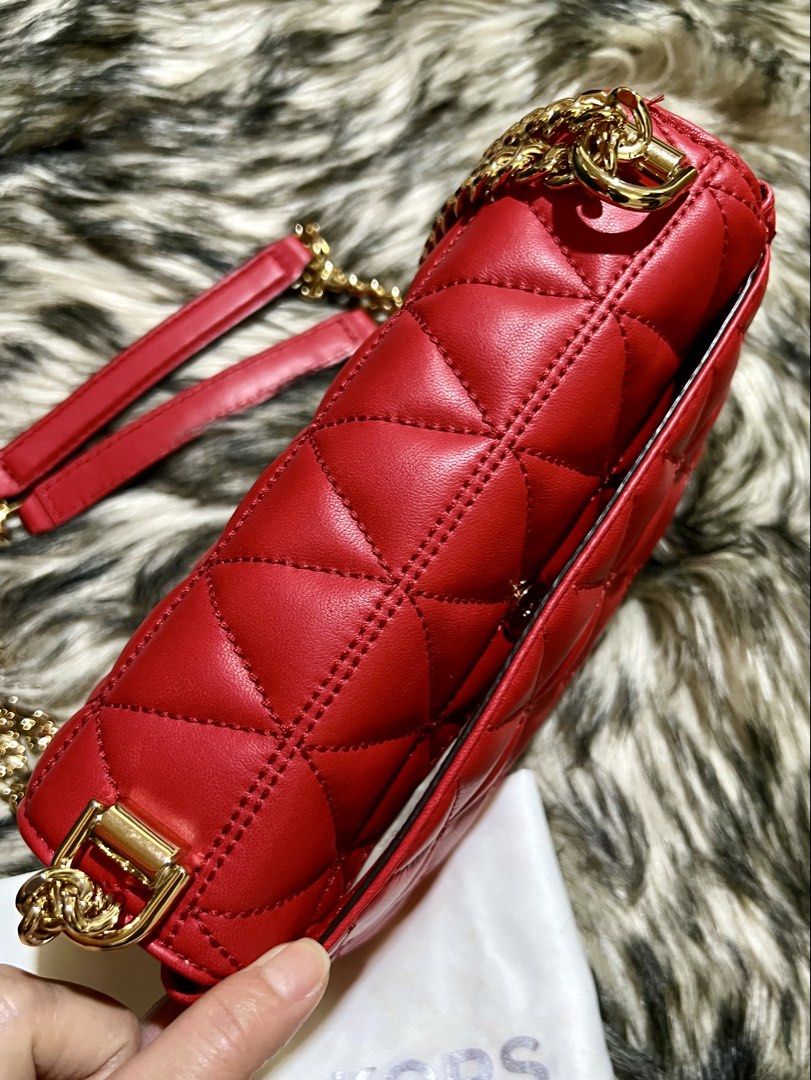Michael Kors Sloan Small Shoulder Bag (Category: Luxury Bags & Wallets) located in Manila. Submitted by the_realmgrace (Listing ID 1426999633, Image 3). Description: Michael Kors shoulder bag features a quilted design and a chain strap. It has a rectangular shape with a gold-tone clasp closure. The interior includes a zippered pocket. The bag is red and comes with a dust bag. The chain strap has a leather shoulder rest for comfort..