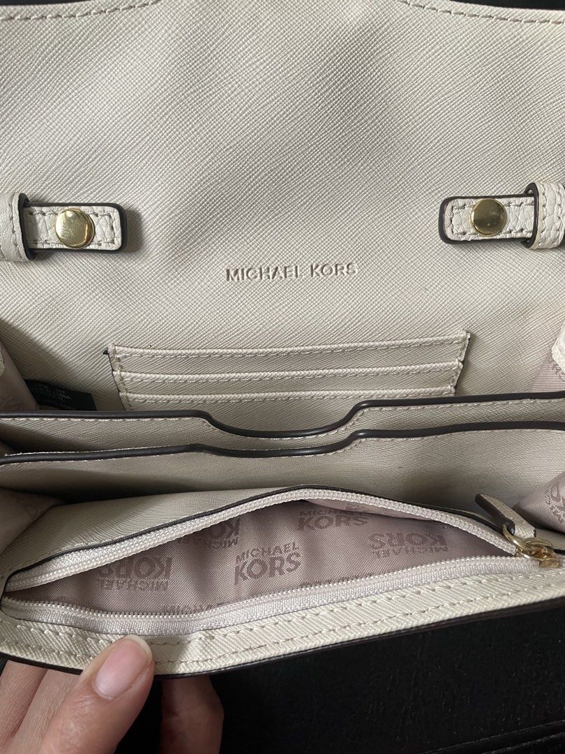 Michael Kors Off White Sling Wallet (Category: Luxury Bags & Wallets) located in Cabanatuan. Submitted by moraiahraven (Listing ID 1427061826, Image 3). Description: Michael Kors crossbody bag features a white exterior with a gold chain strap. The bag has a flap closure with the MK logo in the center. The interior includes multiple compartments and the Michael Kors logo. It also has a detachable strap. The bag is suitable for carrying essentials.