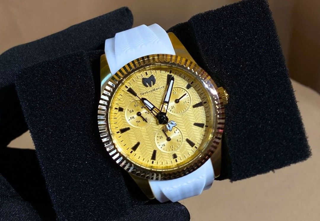 Technomarine Chronograph Watch (Category: Men's Watches) located in Bulacan. Submitted by virijennifer-21966 (Listing ID 1426971739, Image 3). Description: Stylish Technomarine chronograph watch with a gold-tone bezel and a vibrant blue dial. Features a blue silicone strap. The watch has three sub-dials and a date display. The second watch has a gold dial and a white strap. Both watches are presented in a black display case..