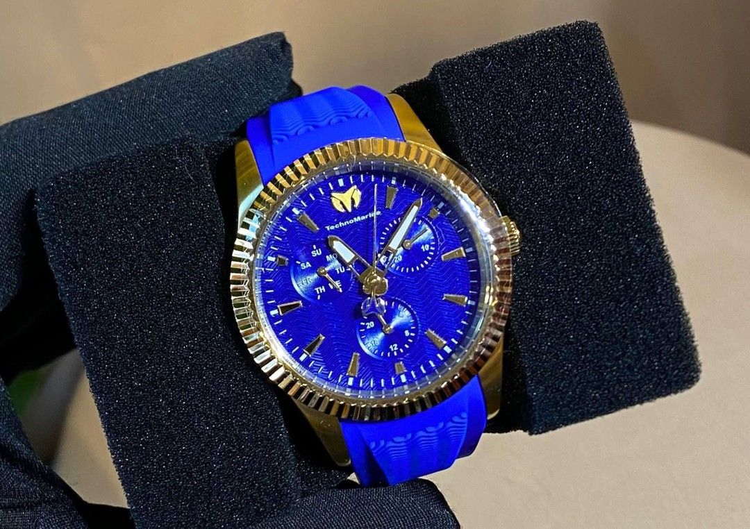 Technomarine Chronograph Watch (Category: Men's Watches) located in Bulacan. Submitted by virijennifer-21966 (Listing ID 1426971739, Image 1). Description: Stylish Technomarine chronograph watch with a gold-tone bezel and a vibrant blue dial. Features a blue silicone strap. The watch has three sub-dials and a date display. The second watch has a gold dial and a white strap. Both watches are presented in a black display case..